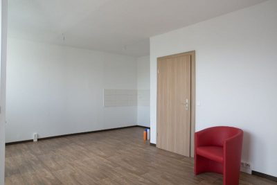 Ein leeres Wohnzimmer mit einem roten Sessel.